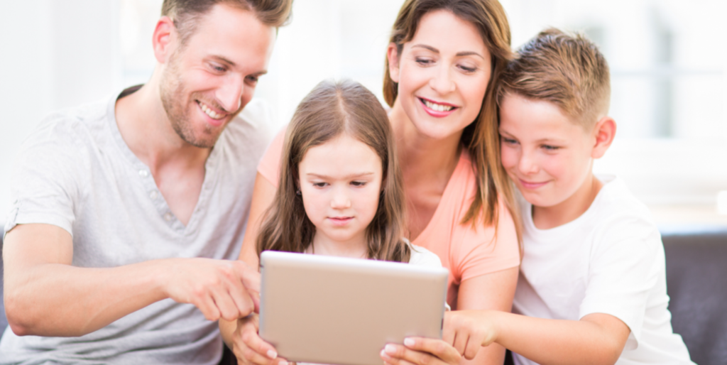 Mutter und Vater mit Mädchen und Junge am Tablet.