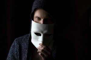 Person hält sich eine Maske vor dem Gesicht.
