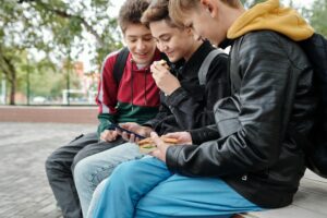 Drei Jungs sitzen mit dem Smartphone.
