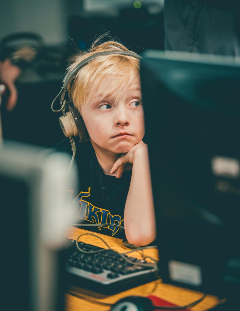 Junge sitzt vor PC und trägt Kopfhörer.