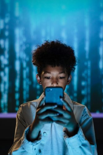 Ein Junge schaut in sein Smartphone.