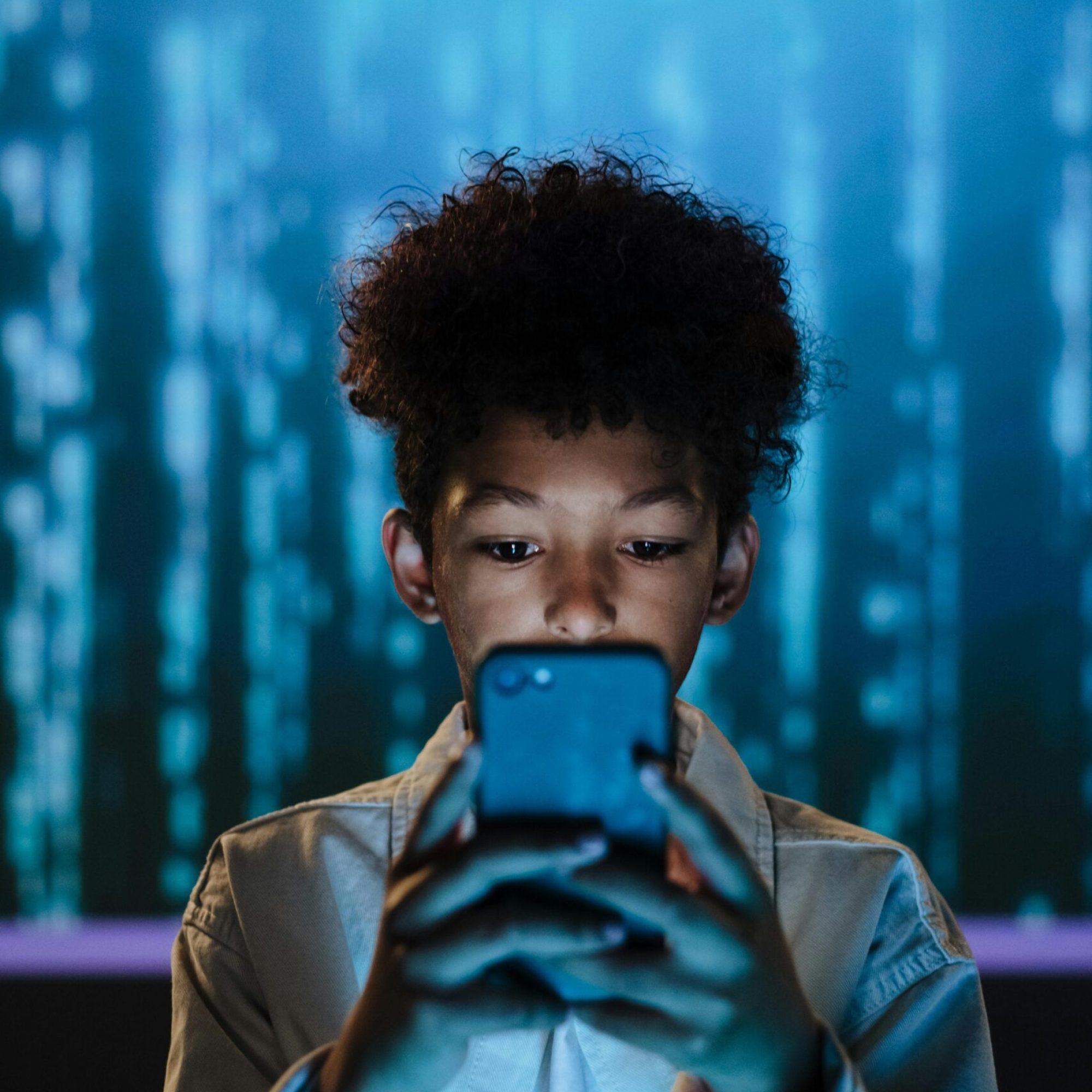 Ein Junge schaut in sein Smartphone.